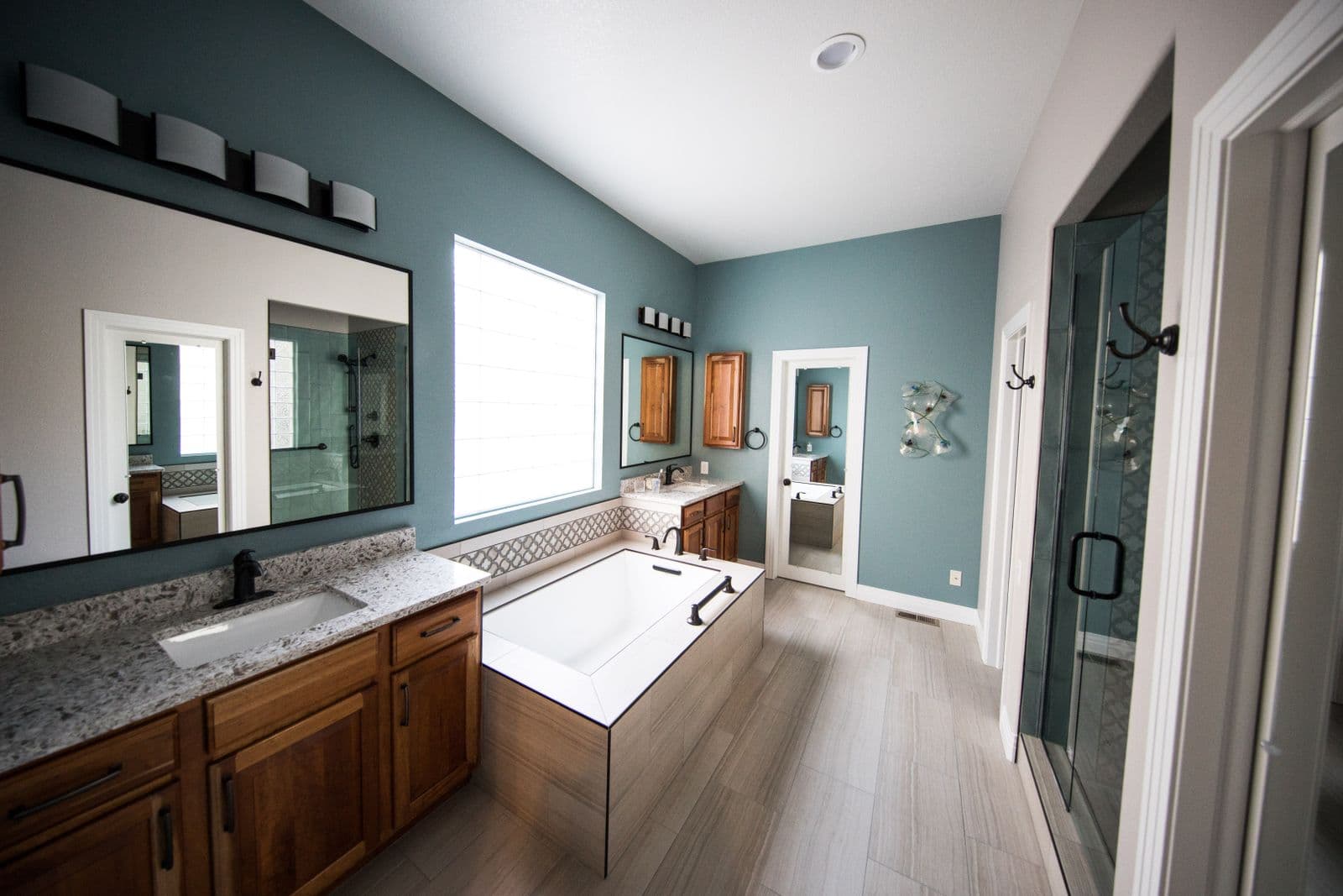 Remodeled master bathroom with frameless glass walk-in shower and patterned accent tile