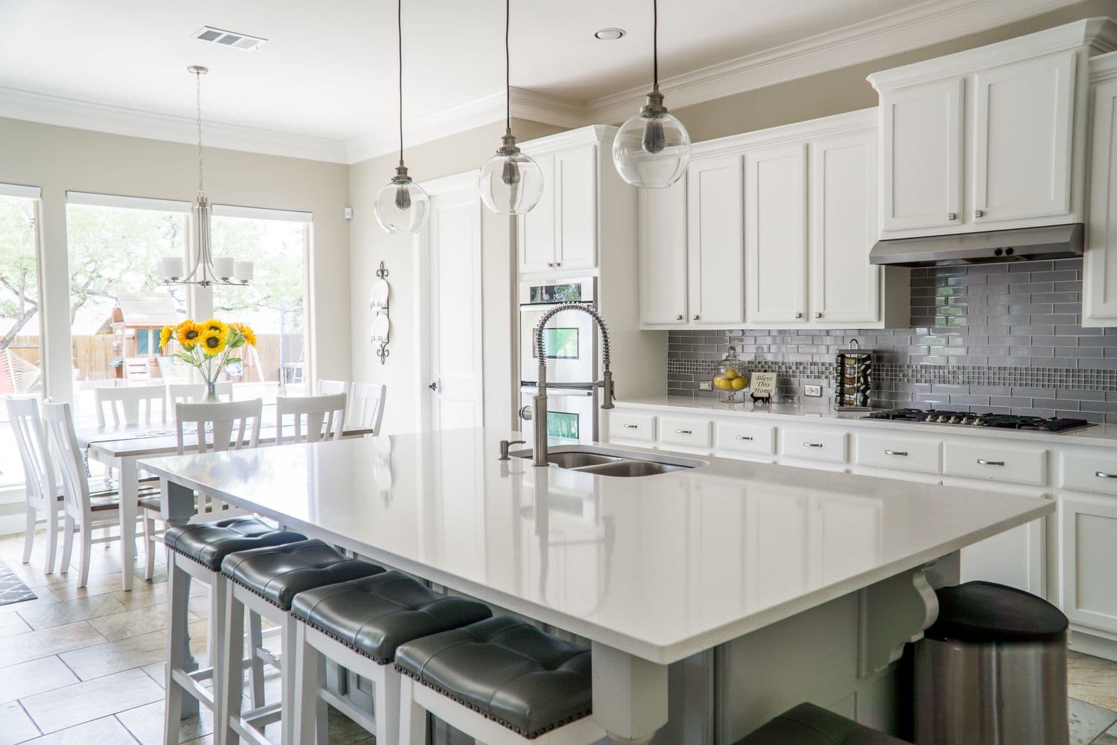 Remodeled Arlington kitchen with white custom cabinetry, large quartz island, and pendant lighting